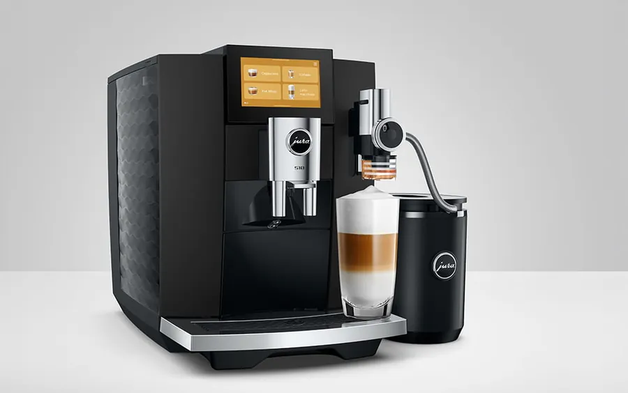 JURA S10 en negro con pantalla táctil, depósito de leche y un café con leche en capas en un vaso